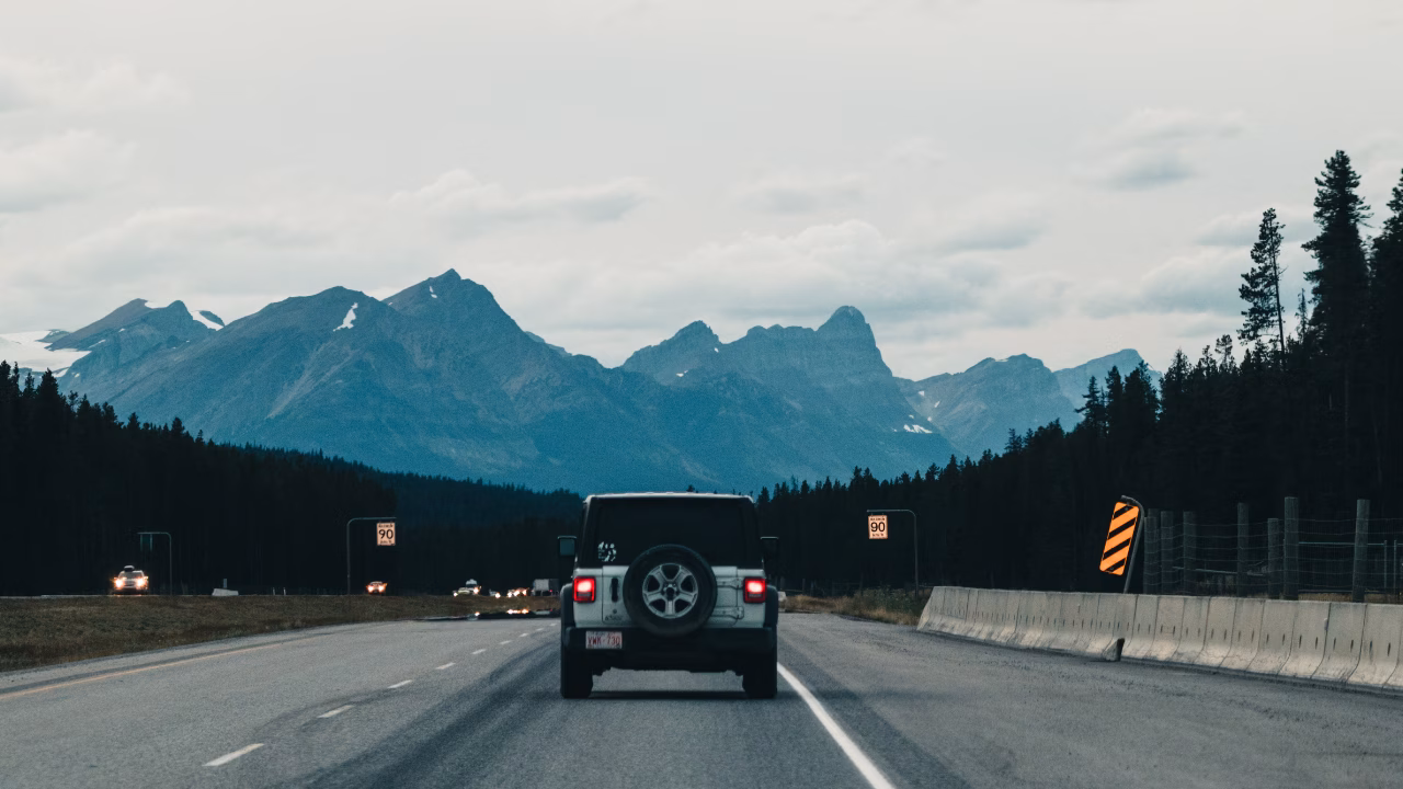 Car travelling along an open road with mountains ahead.