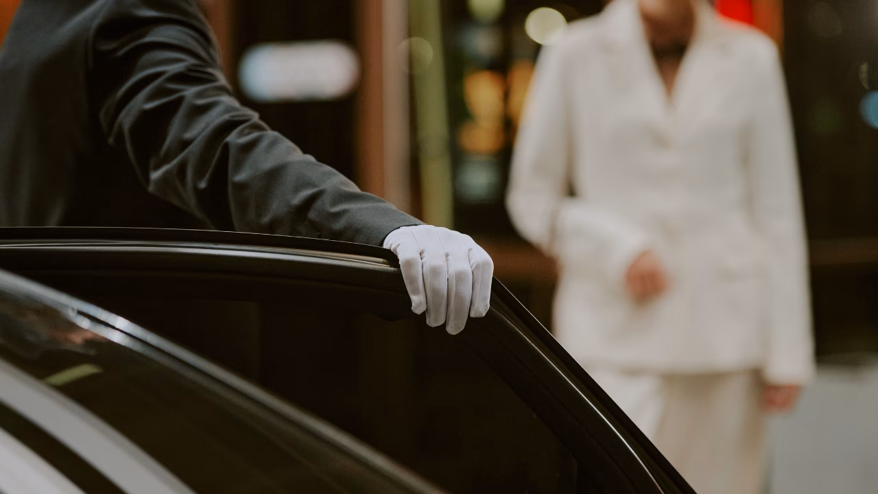 Chauffeur holding a car door open for a waiting passenger.