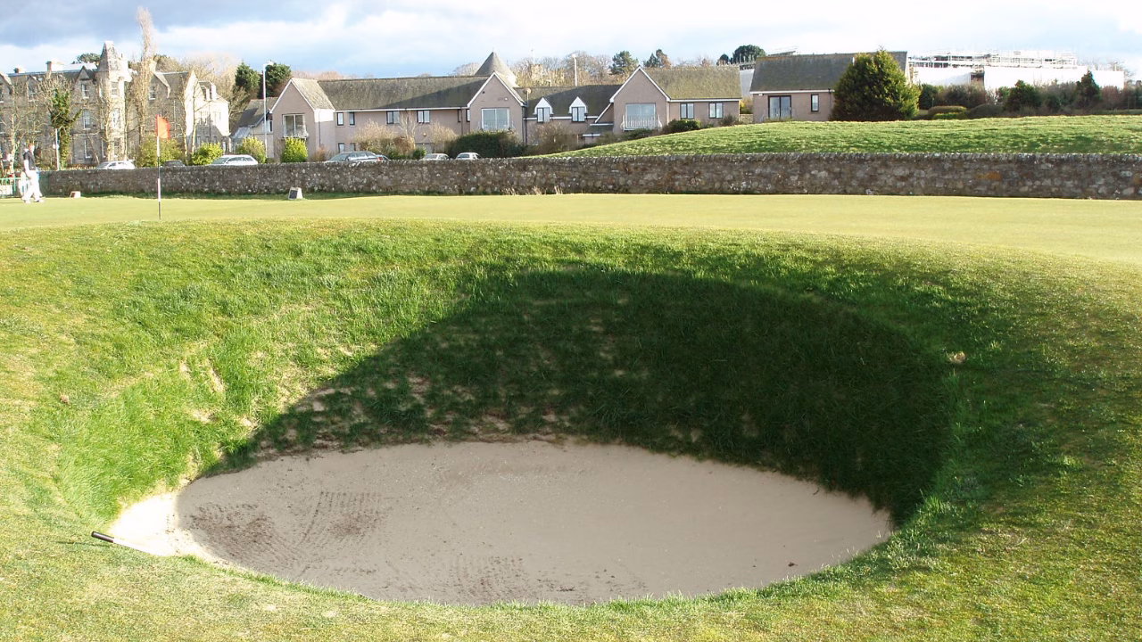 Road Hole Bunker beside the 17th green with the stone boundary wall beyond.