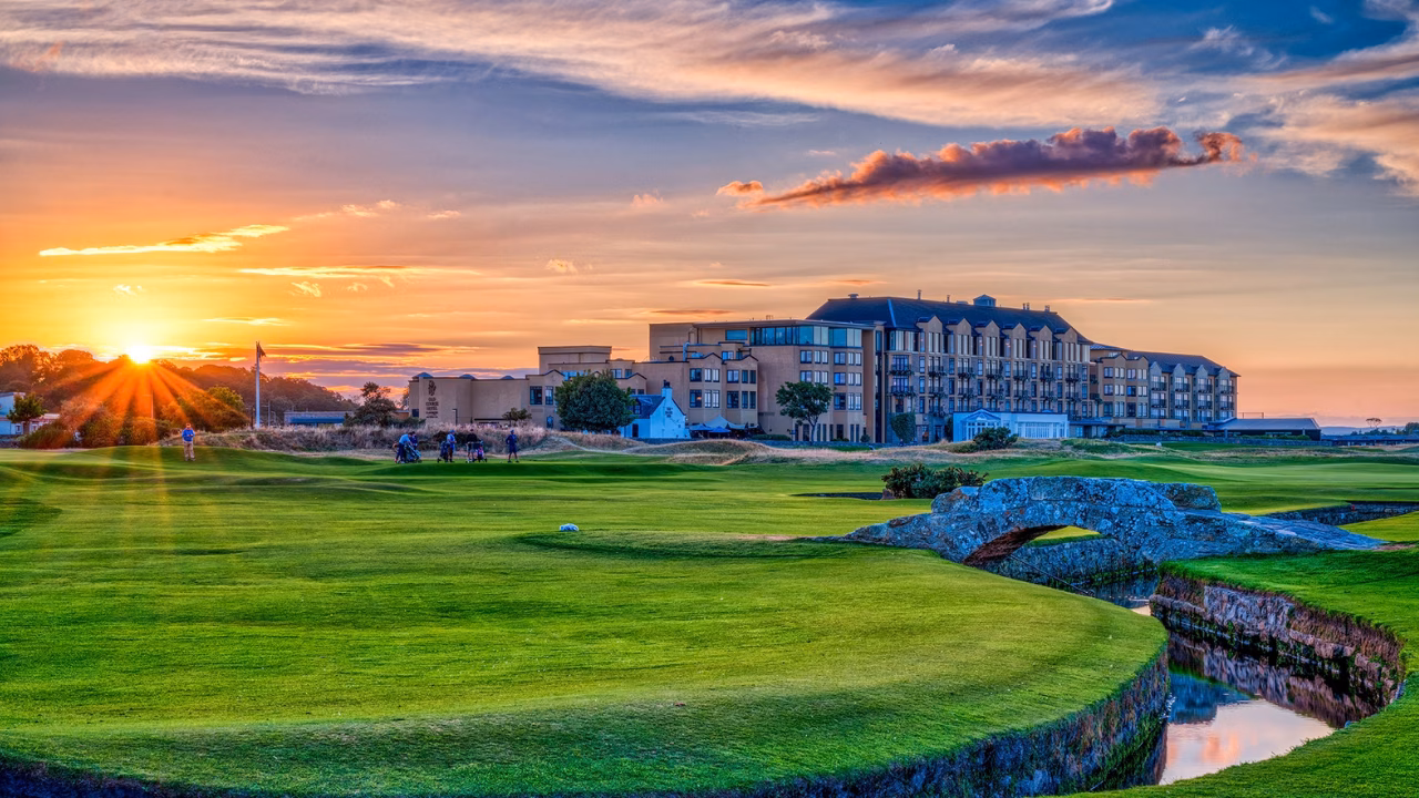 Swilcan Bridge on the Old Course with Old Course Hotel in the background at sunset.