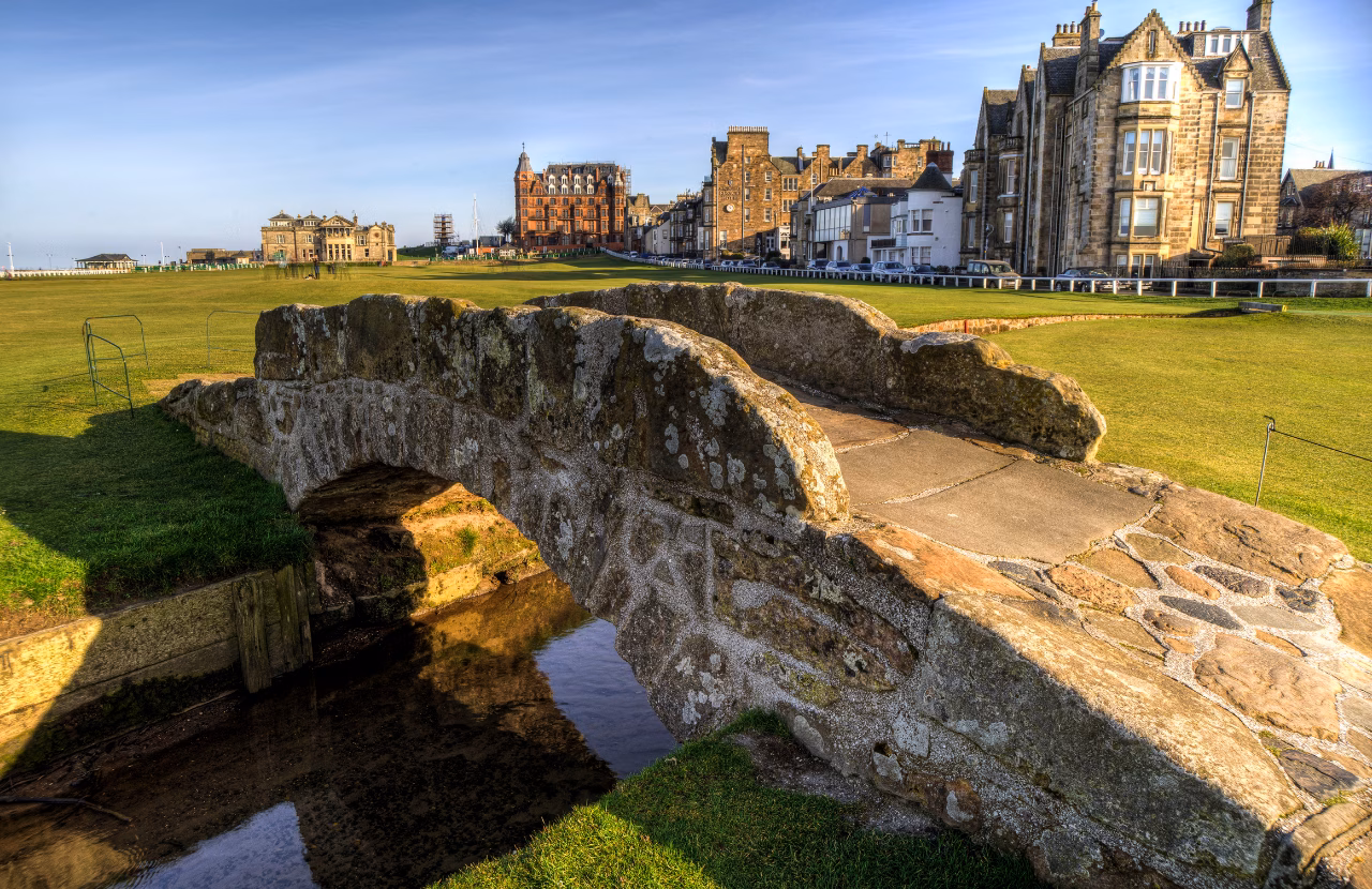 Close view of the Swilcan Bridge with St Andrews buildings beyond.
