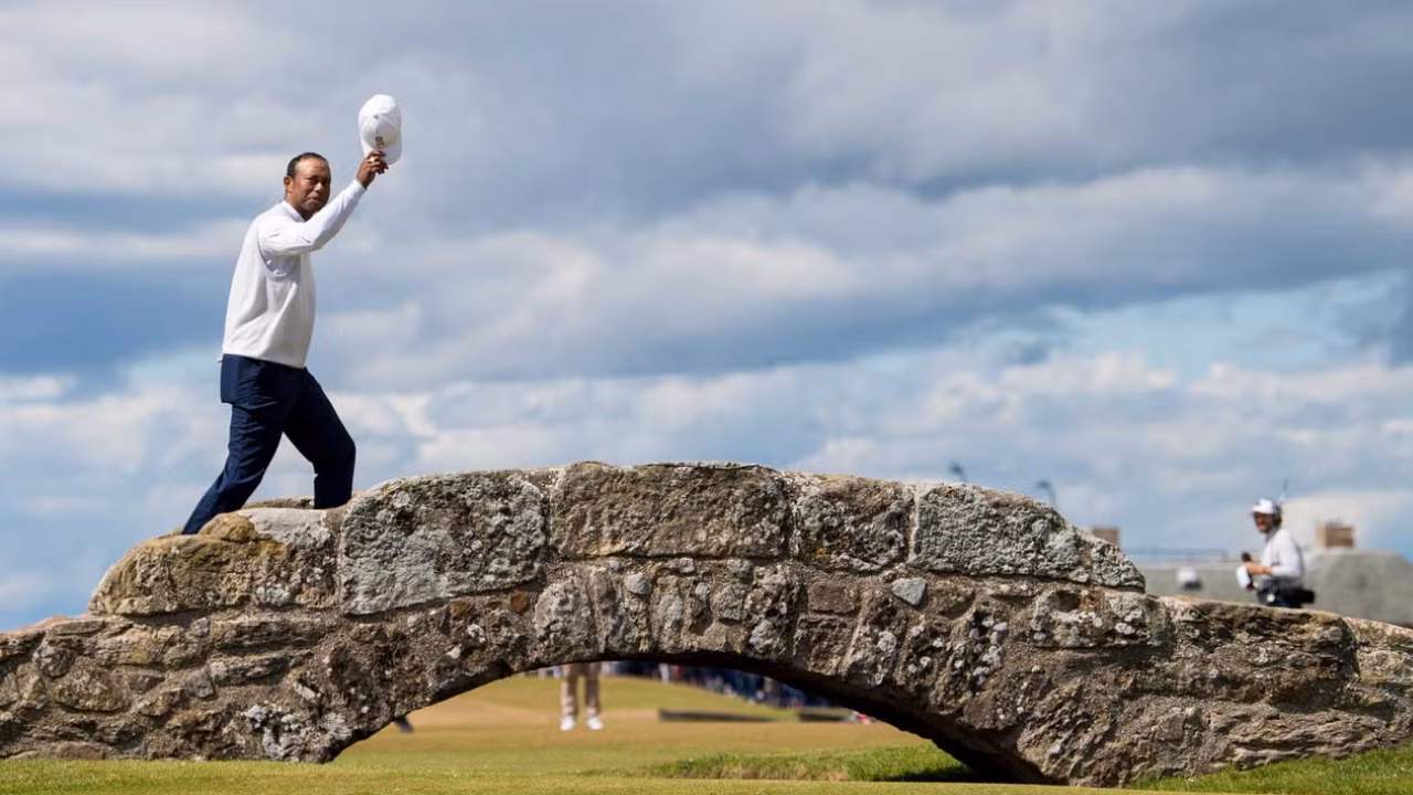 Tiger Woods waving to the crowd while crossing the Swilcan Bridge at The Open in 2022.